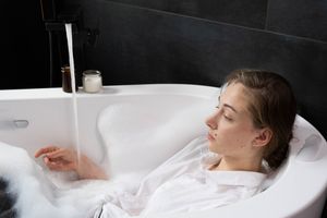 Woman soaking in a bathtub, lost in deep thought, highlighting themes of relaxation and mental health.